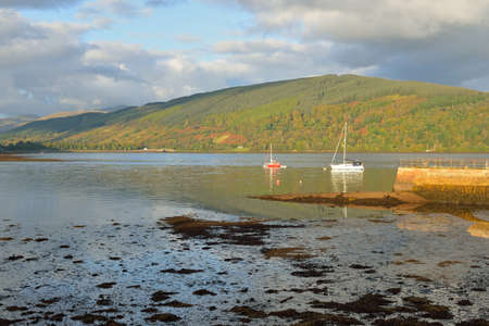 Sailboat anchored in lake. Majestic forest hills. Scotland, UK. Atmospheric landscape. Travel...