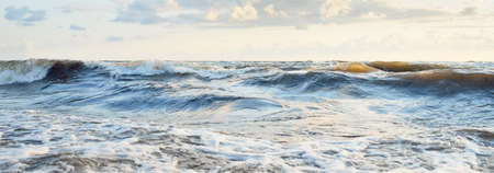 Baltic sea shore after the storm. Sunset, soft golden sunlight. Water surface texture, crashing...