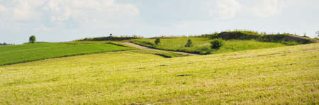 Green hills of a plowed agricultural field and forest. Idyllic summer rural scene. Dramatic sky...