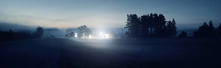 Country highway (asphalt road) in a fog at sunset. Filling station in the background. Moonrise, twilight, moody sky. Idyllic rural scene. Transportation, infrastructure, car serviceの写真素材