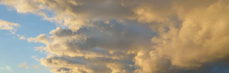 Clear blue sky with glowing pink and golden clouds after the storm. Dramatic sunset cloudscape....