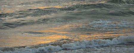 Baltic sea shore after the storm. Sunset, soft sunlight. Water surface texture, crashing waves and...