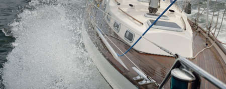 Old classic yacht sailing in an open sea during the storm. Wooden teak deck. Ketch sailboat. Waves,...