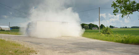Semi-trailer truck on the country road with a sharp turn. Speed, clouds of dust. Freight...