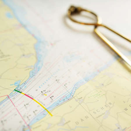 Antique W HC 6" brass dividers calipers nautical navigation chart tool and white map close-up. Vintage still life. Sailing, travel accessories. Planning, concept art, graphic resources, copy spaceの写真素材