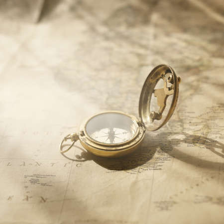 Retro style antique golden compass (sundial) and old nautical chart close-up. Vintage still life. Sailing accessories. Wanderlust, travel and navigation theme. Graphic resources, copy spaceの写真素材