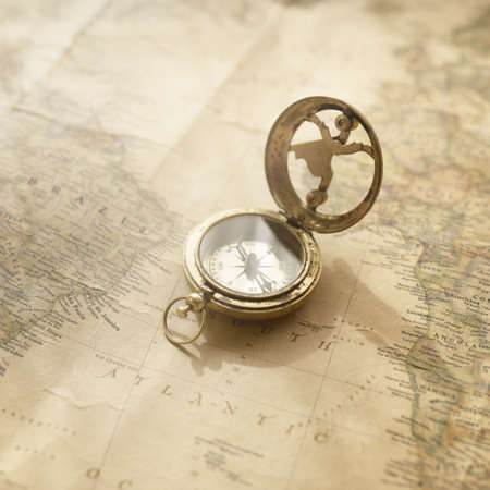 Retro style antique golden compass (sundial) and old nautical chart close-up. Vintage still life. Sailing accessories. Wanderlust, travel and navigation theme. Graphic resources, copy spaceの写真素材