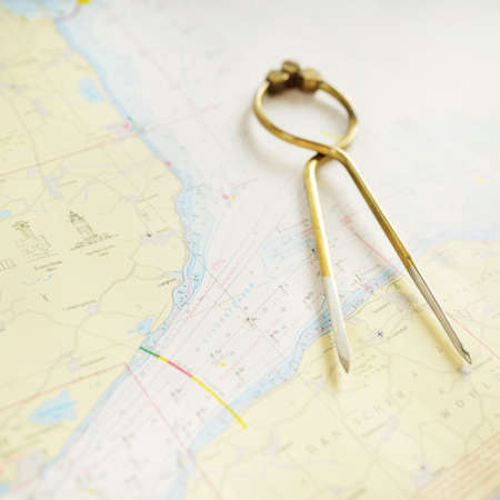 Antique W HC 6" brass dividers calipers nautical navigation chart tool and white map close-up. Vintage still life. Sailing, travel accessories. Planning, concept art, graphic resources, copy spaceの写真素材