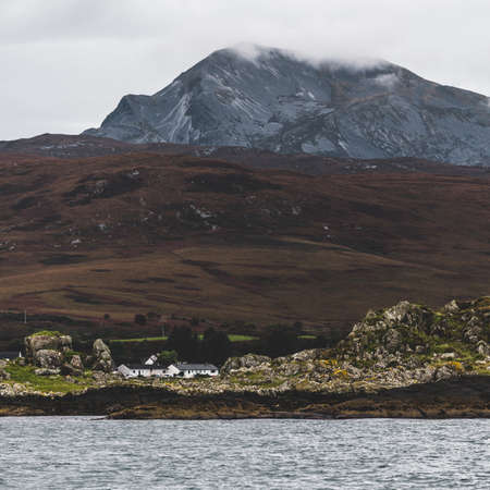 Rocky shore near the highest mountain peak of Paps of Jura (Beinn an Ã’ir) under the cloudy blue...