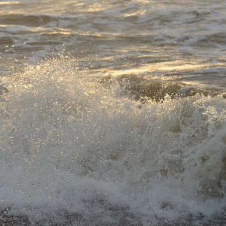 Baltic sea shore after the storm. Sunset, soft sunlight. Water surface texture, crashing waves,...