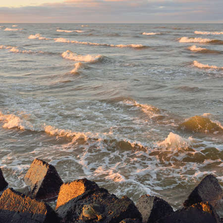 View from the old pier. Breakwaters close-up. Dramatic sunset sky, golden sunlight. Seascape,...