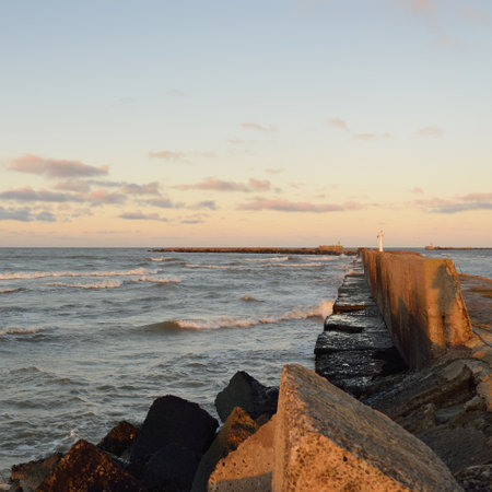 View from the old pier. Breakwaters close-up. Dramatic sunset sky, golden sunlight. Seascape, cloudscape. Baltic sea. Spring. Tourism, landmark, navigationの写真素材