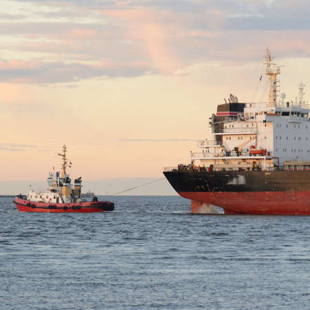 Large cargo ship arriving in port at sunset. Baltic sea.  Freight transportation, nautical vessel,...