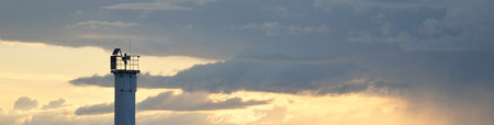 Lighthouse with a solar battery. Baltic sea. Dramatic sunset sky after the storm. Glowing clouds,...
