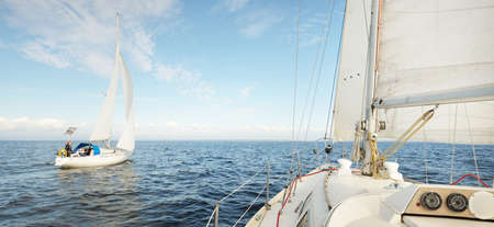 White sloop rigged yacht sailing in an open sea. Clear sky, cloudscape. A view from the sailboat....