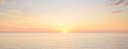 Baltic sea shore under a blue sky with glowing pink and golden sunset clouds. Rocky shore, breakwaters. Idyllic seascape. Latvia. Nature, environmental conservation, ecotourism. Picturesque sceneryの写真素材