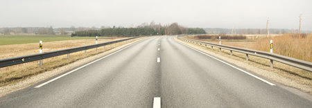 Panoramic view of the empty highway (new asphalt road) through the fields on a sunny spring day....