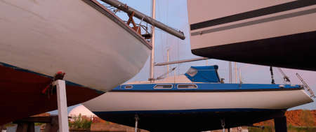 Elegant and modern sailboats standing on land in a yacht club (marina) at sunset. Sailing, cruise,...