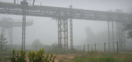 Piping system of a metallurgical factory in a thick white fog. Dark urban landscape. Nature,...