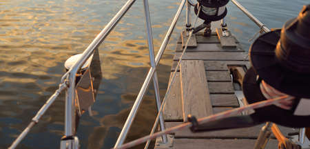 Old classic sailboat with wooden teak deck moored to a pier in a yacht marina at sunset. Vacations,...