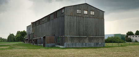 An old dark wooden warehouse under dramatic clouds. Storm weather, hurricane. Atmospheric summer...