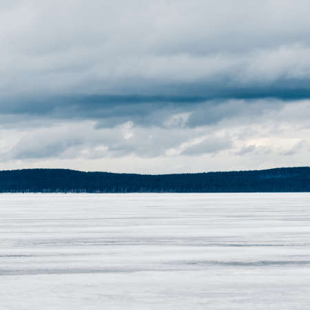 Frozen forest lake at sunset. Dramatic sky. Winter landscape. Karelia, Russia. Nature, ecology, environment, weatherの写真素材