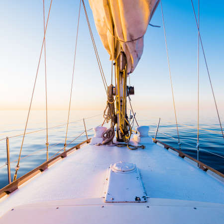 Sloop rigged yacht sailing in a still water after the storm. Sunset. Reflections on water. Baltic...