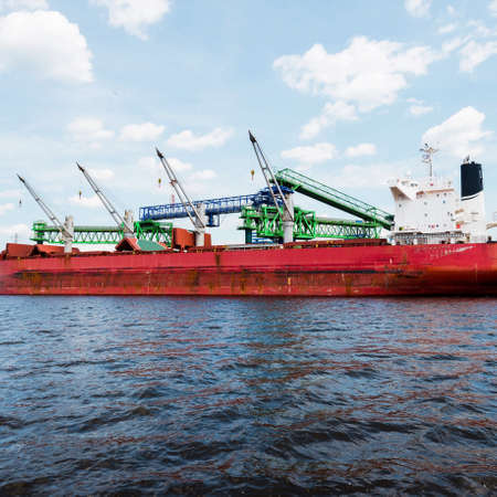 Large cargo ship loading in port terminal. Panoramic view. Freight transportation, nautical vessel,...