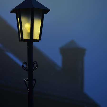 Street light and a castle wall in a fog at night. Mysterious light. Atmospheric urban scene, panoramic imageの写真素材