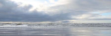 Baltic sea after the storm. Soft sunset light, dramatic glowing clouds. Seascape, cloudscape, nature. Reflections on water. Panoramic view. Ecology, climate change, weatherの写真素材