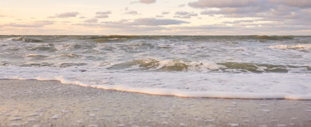 Baltic sea shore (sand dunes) at sunset. Soft sunlight, clear sky with glowing clouds, waves and...