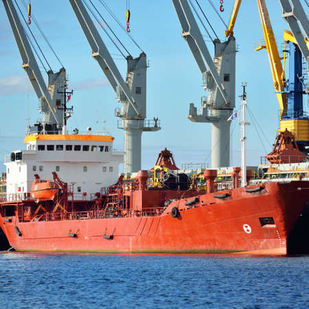 Cargo ships loading in port terminal. Cranes in the background. Baltic sea. Bunkering, fuel and...