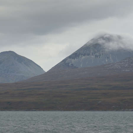 Rocky lake shore, mountain peaks, mountains, valleys and hills. Panoramic view from a sailboat....