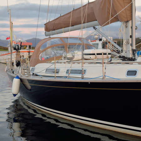 Elegant and modern sailboats moored to a pier in a yacht marina at sunset. Dramatic clouds. Inner...