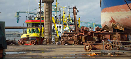 Old cargo ship standing on land. Harbor, shipyard. Dark industrial scene. Transportation, repair, service, destruction, environmental damage, third world, economic problemsの写真素材