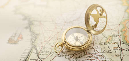 Retro style antique golden compass (sundial) and old nautical chart close-up. Vintage still life. Sailing accessories. Wanderlust, travel and navigation theme. Graphic resources, copy spaceの写真素材