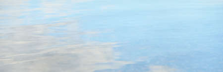 Reflections of a blue sky in a crystal clear water. Natural texture, background, graphic resources. Nature, environment, summer vacations, beach themeの写真素材