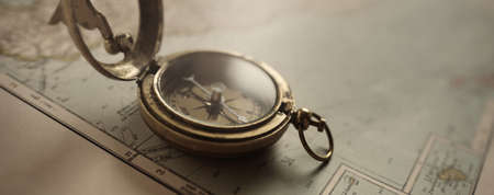 Retro style antique golden compass (sundial) and old nautical chart close-up. Vintage still life. Sailing accessories. Wanderlust, travel and navigation theme. Graphic resources, copy spaceの写真素材