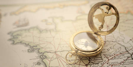 Retro style antique golden compass (sundial) and old nautical chart close-up. Vintage still life. Sailing accessories. Wanderlust, travel and navigation theme. Graphic resources, copy spaceの写真素材