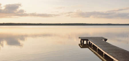 Forest lake (river) at sunset. Wooden pier. Glowing clouds, symmetry reflections in a still crystal clear water. Idyllic landscape. Nature, ecology, ecological reserve, ecotourism, hiking, vacationsの写真素材