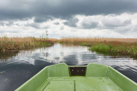 Small green boat anchored in forest lake. Scandinavia. Transportation, traditional craft, recreation, leisure activity, healthy lifestyle, local tourism, sport, rowing, hiking, summer vacations themesの写真素材