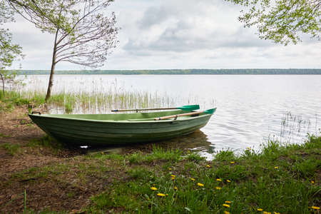 Small green boat anchored in forest lake. Scandinavia. Transportation, traditional craft,...