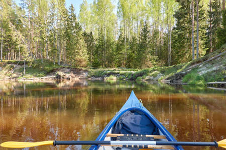 Canoe riding on Irbe river. Kurzeme, Latvia. Forest. mighty trees, reflections in water. Nature, ecology, eco tourism, hiking, leisure activity, boating, rowing, sport, healthy lifestyle, wanderlustの写真素材