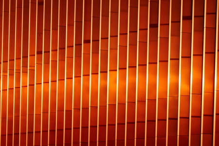 Modern building, exterior elements close-up.Red, orange, golden color. Reflection. Concept urban scene, texture, background, wallpaper. Architecture, urbanisation, cast-in-place concrete technologyの写真素材