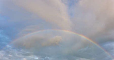 Rainbow. Ornamental clouds. Dramatic sky after the storm and rain. Soft sunlight. Panoramic image,...