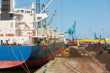 Large ship loading in port terminal. Cranes, excavators, railway, cargo train. Freight...