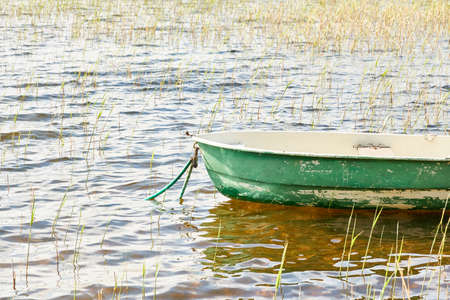 Small green boat anchored in forest lake. Scandinavia. Transportation, traditional craft, recreation, leisure activity, healthy lifestyle, local tourism, sport, rowing, hiking, summer vacations themesの写真素材