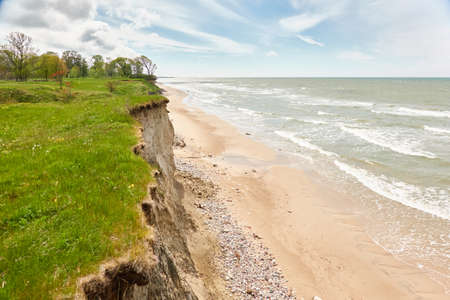 Baltic sea shore on a sunny day. Sand dunes, dune grass. Picturesque panoramic aerial view. Nature, environment, fickle weather, cyclone. Summer vacations, travel destinations, hiking, eco tourismの写真素材
