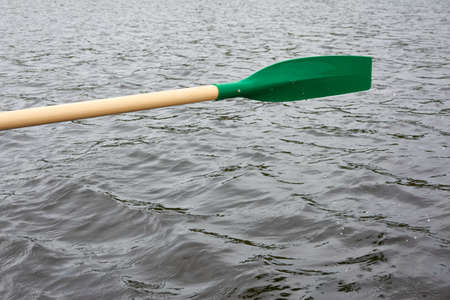 Rowing a small green boat on the forest lake. Paddle close-up. Dramatic sky. Reflections on water....