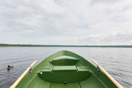 Rowing a small green boat on the forest lake. Wild duck (mallard) in the background. Transportation,...
